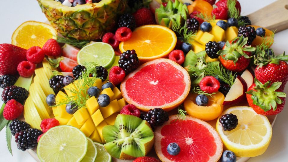 Rôzne druhy ovocia na tanieri, vrátane ananásu, mango, kiwi a bobúľ.