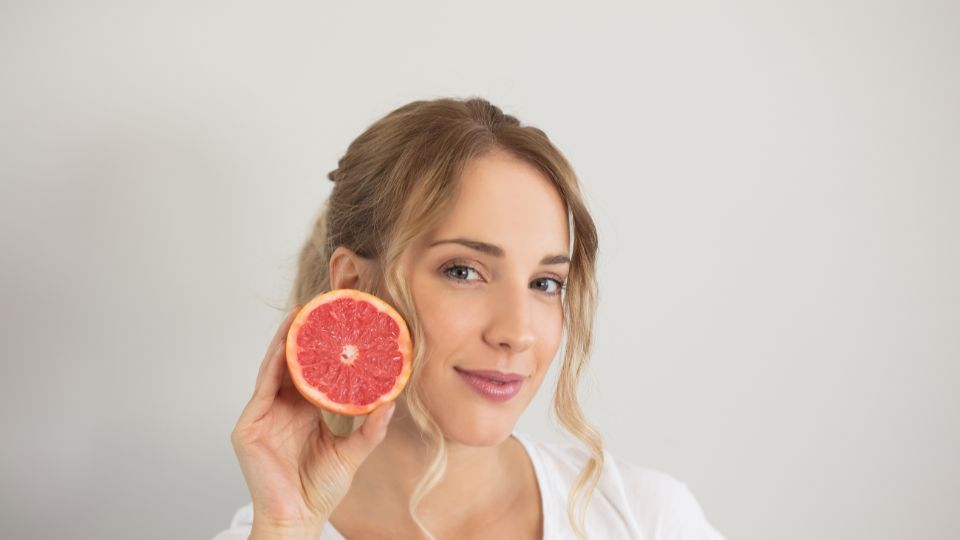Žena s grapefruitom, symbolizujúca zdravú stravu pre športovcov.